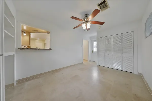 an empty room with windows and fan