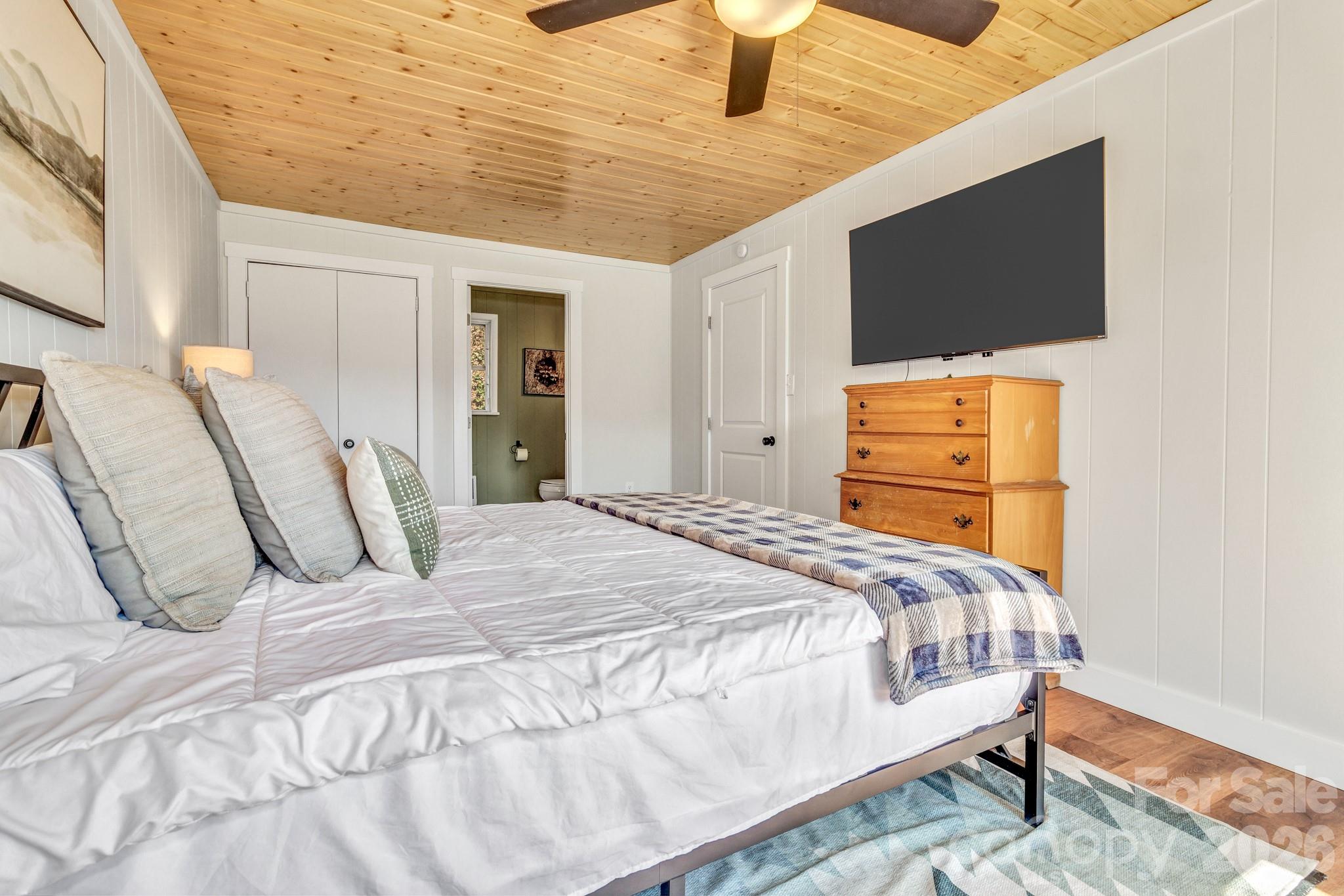 80 Hidden Falls Road Maggie Valley, NC 28751 - Photo 31 of 47 a bedroom with a bed tv and wooden floor