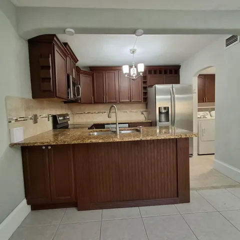a kitchen with granite countertop a sink a counter top space and cabinets
