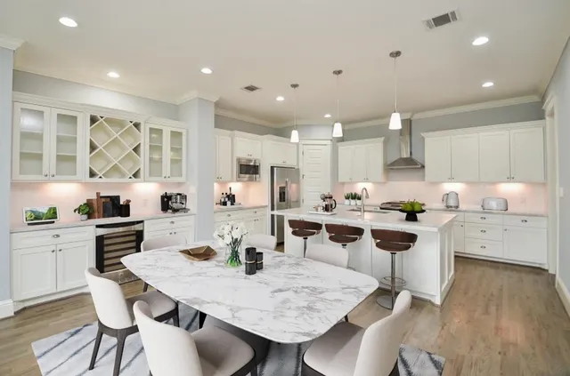 a kitchen with stainless steel appliances kitchen island granite countertop a dining table chairs stove refrigerator and cabinets