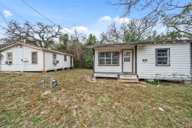 a white house that has a small yard and a large tree