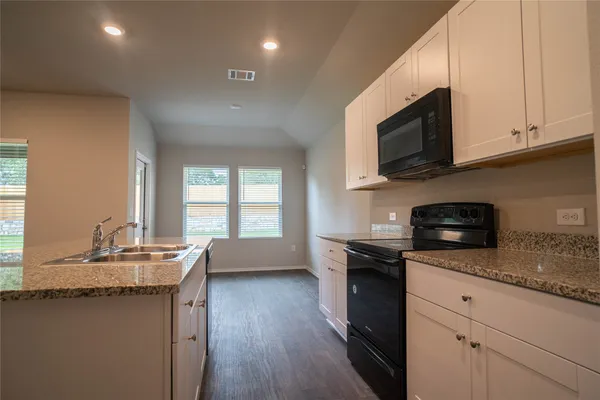 a kitchen with stainless steel appliances granite countertop a sink a stove a microwave and wooden cabinets