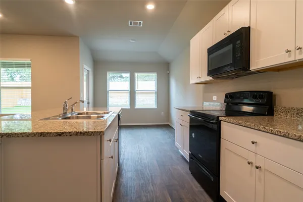 a kitchen with granite countertop a sink dishwasher stove and microwave with wooden floor