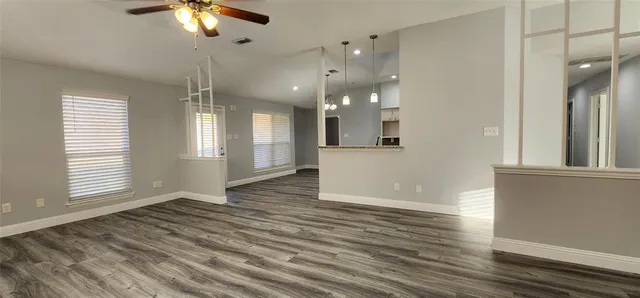 an empty room with wooden floor and windows