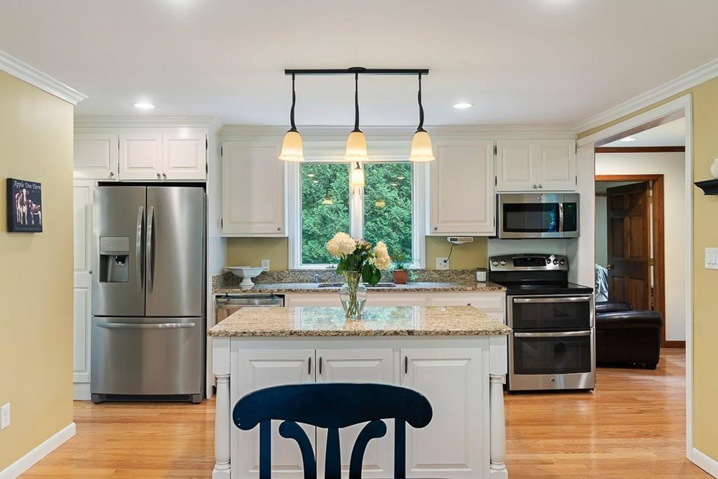 206 Prospect Street Carlisle, MA 01741 - Photo 4 of 25 a kitchen with stainless steel appliances granite countertop a refrigerator a stove a sink a microwave a dining table and chairs with wooden floor