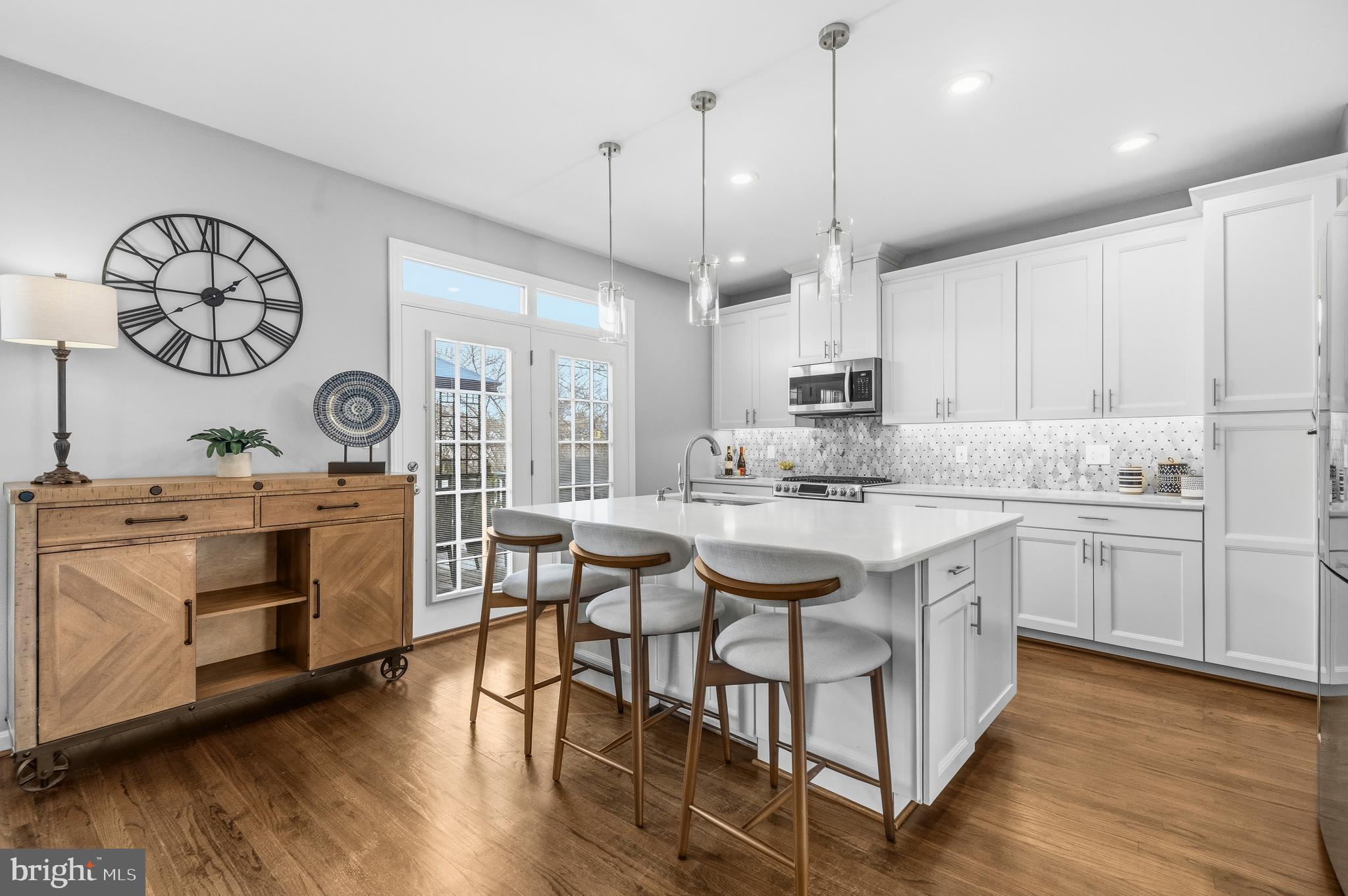 12138 Chancery Station Circle Reston, VA 20190 - Photo 11 of 54 a kitchen with kitchen island granite countertop a stove a sink and white cabinets with wooden floor