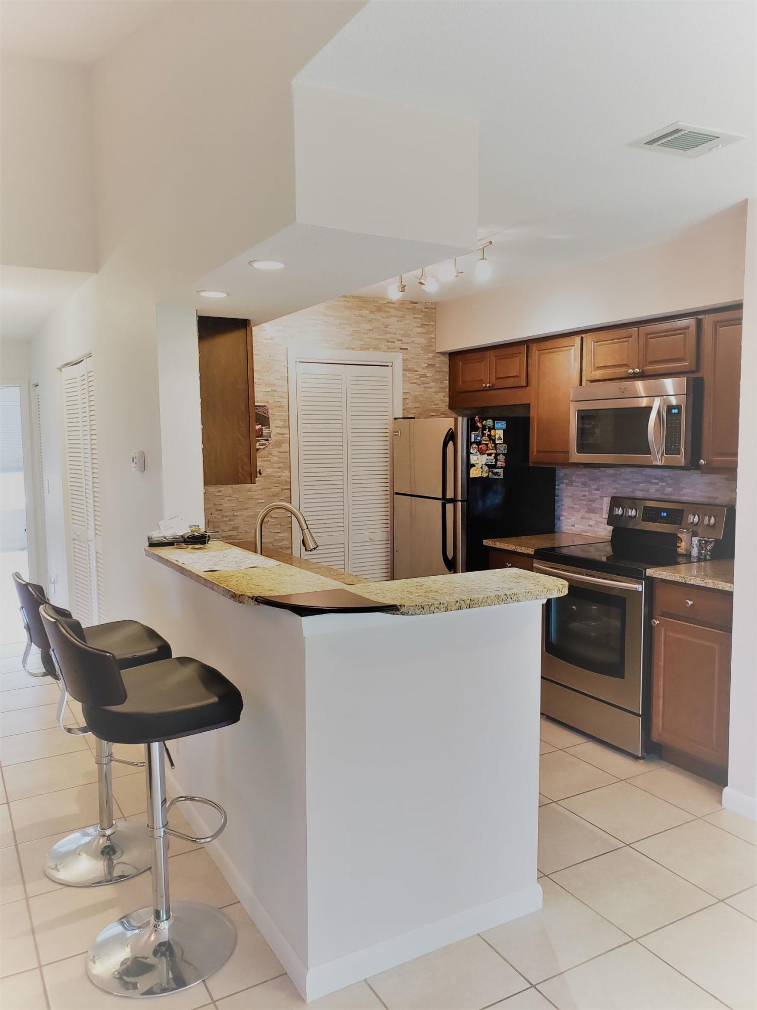 a kitchen with stainless steel appliances granite countertop a sink and a refrigerator