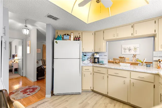 a kitchen with a refrigerator a sink and dishwasher with white cabinets
