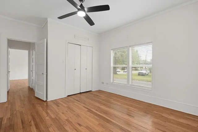 a view of an empty room with wooden floor and a window