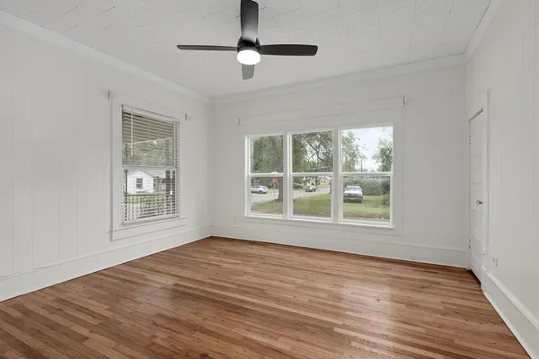 a view of an empty room with wooden floor and a window