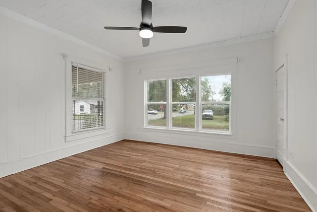 a view of an empty room with wooden floor and a window