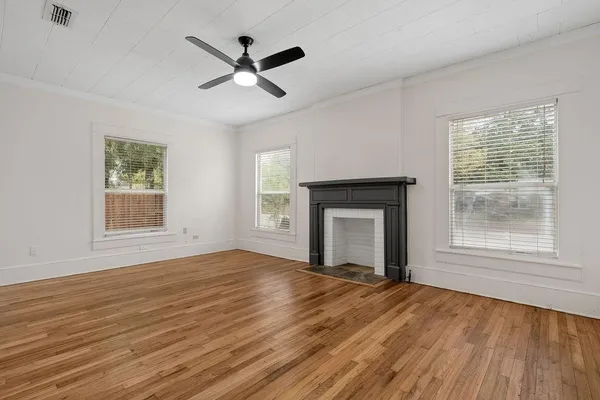 a view of empty room with wooden floor and fan