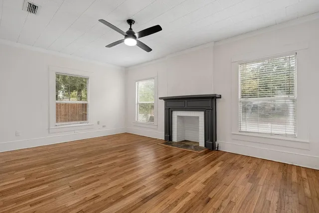 a view of empty room with wooden floor and fan
