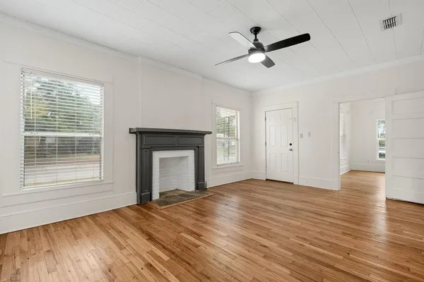 a view of empty room with wooden floor and fan