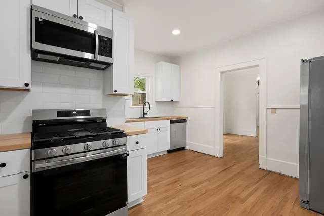 a kitchen with stainless steel appliances a stove microwave and sink