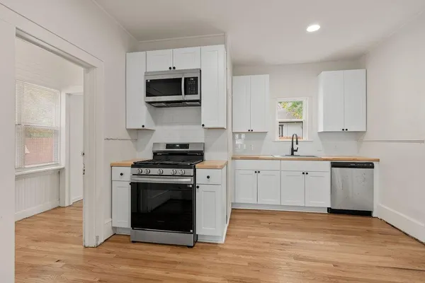 a kitchen with cabinets stainless steel appliances a sink and wooden floor