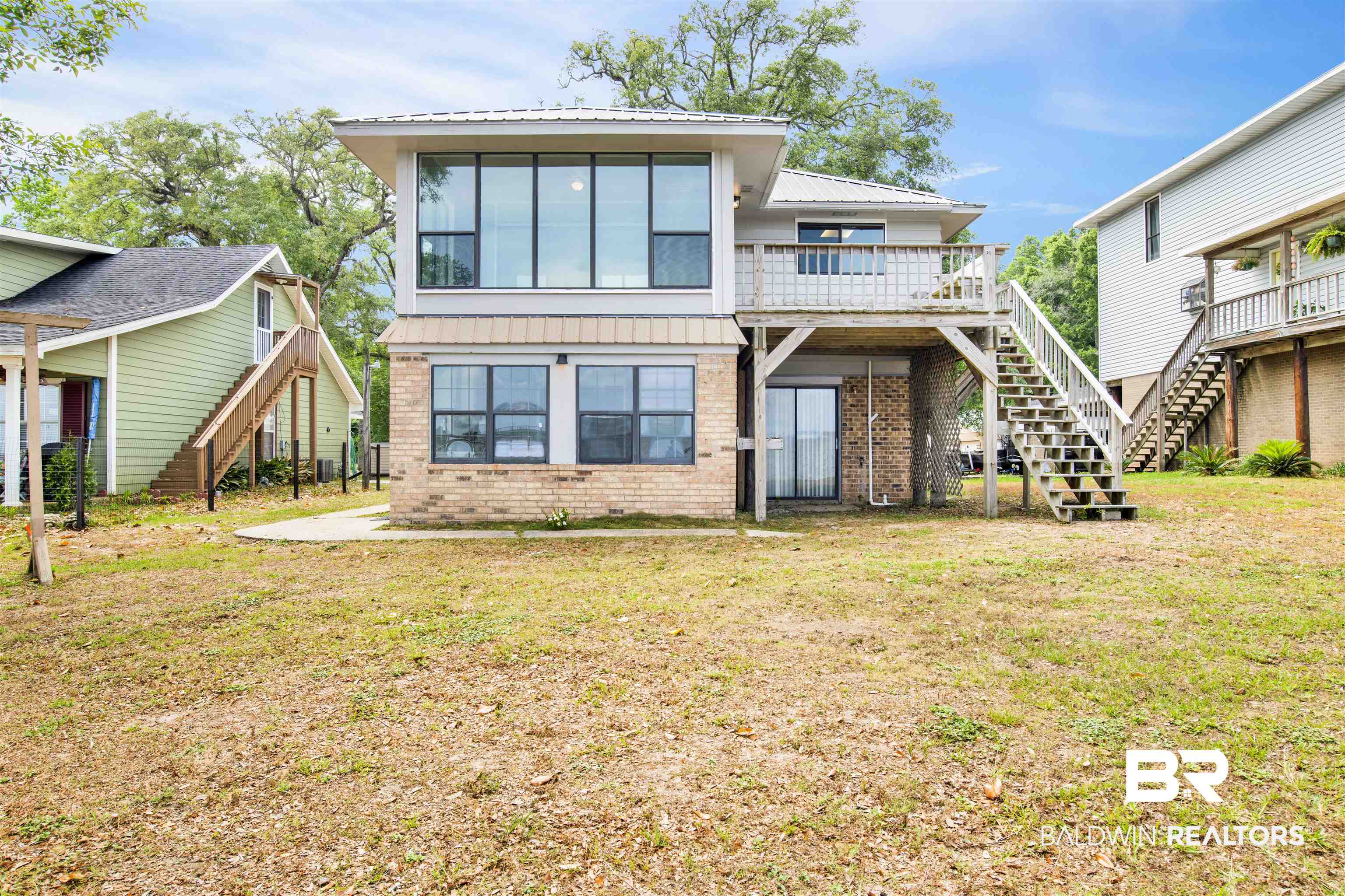 7411 Bay Road Mobile, AL 36605 - Photo 2 of 34 Back of house featuring stairs, brick siding, a lawn, and a patio area
