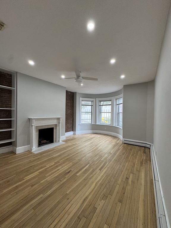 198 St Botolph Street, Unit 2 Boston, MA 02115 - Photo 4 of 10 a view of an empty room with wooden floor fireplace and a window