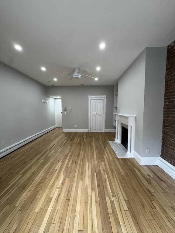 198 St Botolph Street, Unit 2 Boston, MA 02115 - Photo 6 of 10 an empty room with wooden floor and fireplace