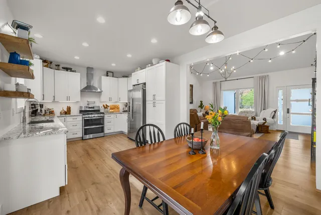 a kitchen with stainless steel appliances granite countertop a sink a stove a dining table and chairs