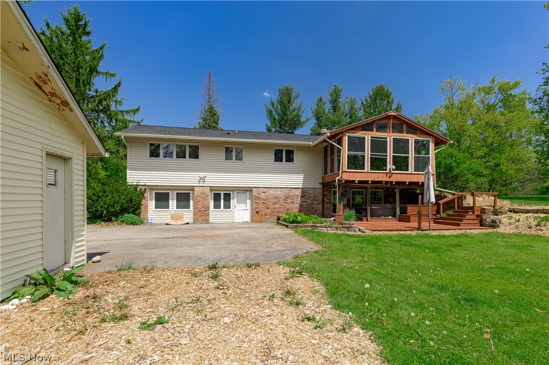 7969 Dines Road Novelty, OH 44072 - Photo 48 of 48 Rear exterior featuring a sun room with wood-finish trim, a multi-level wood-finish deck, and a lower-level brick facade