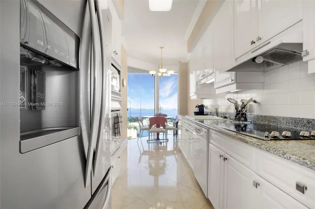 a kitchen with stainless steel appliances a refrigerator a sink dishwasher a stove and white cabinets with wooden floor