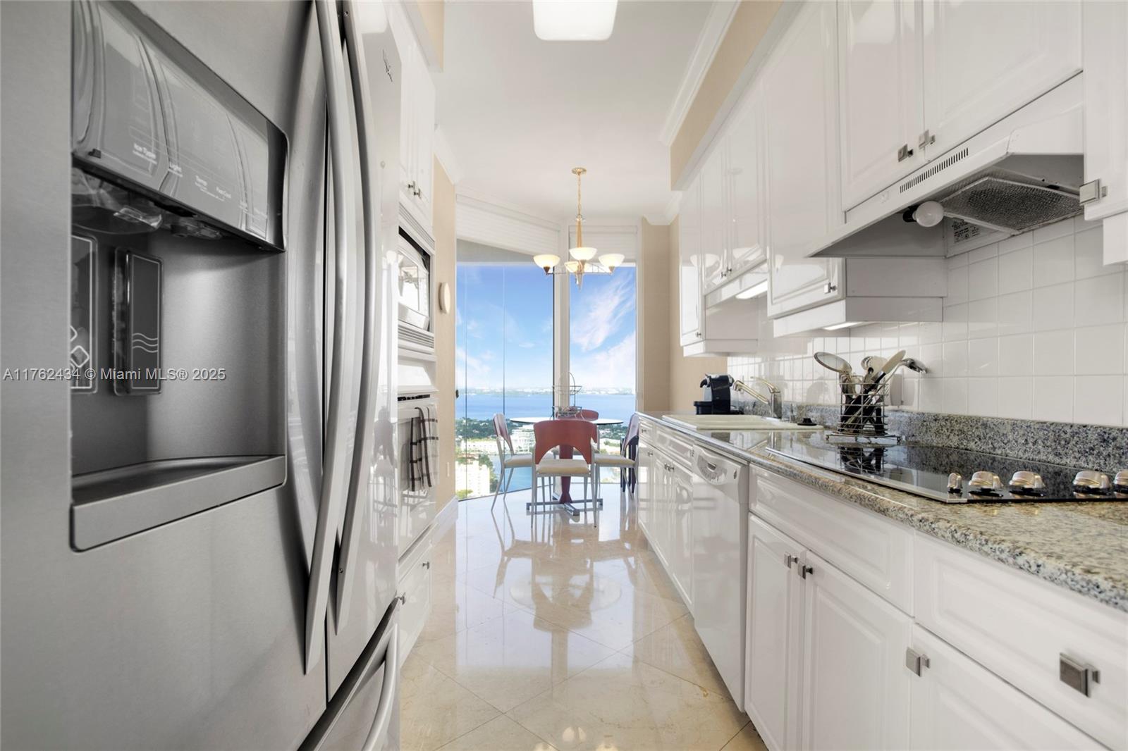 4775 Collins Avenue, Unit 4005 Miami Beach, FL 33140 - Photo 9 of 26 a kitchen with stainless steel appliances a refrigerator a sink dishwasher a stove and white cabinets with wooden floor