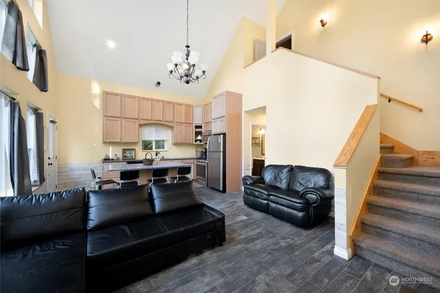 a living room with furniture kitchen view and a chandelier