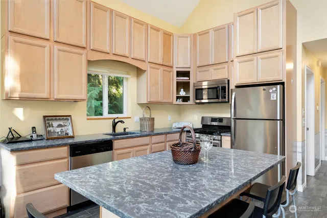 a kitchen with stainless steel appliances granite countertop a sink refrigerator dining table and chairs