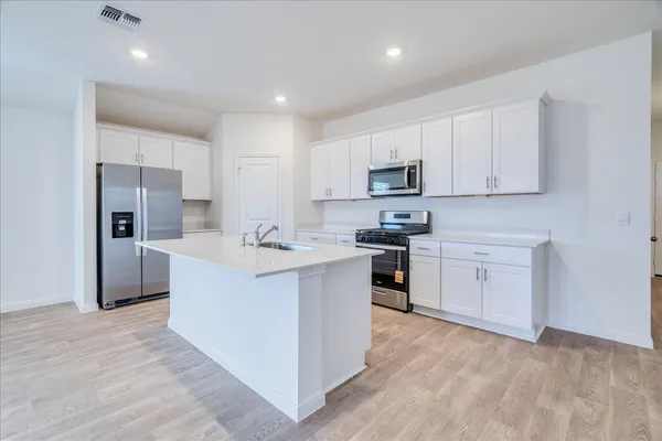 a large kitchen with white cabinets and wooden floor