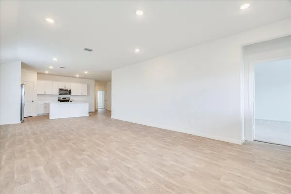 a view of an empty room with wooden floor and windows