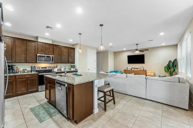 a kitchen with stainless steel appliances kitchen island granite countertop a stove top oven a sink a counter top space and cabinets