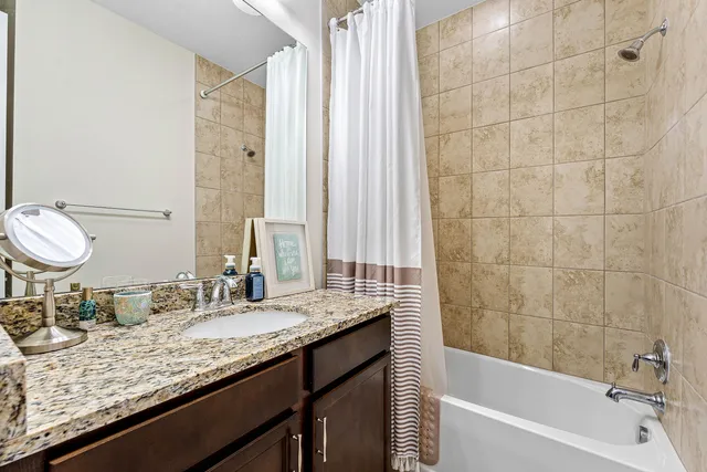 a bathroom with a granite countertop sink and a bathtub