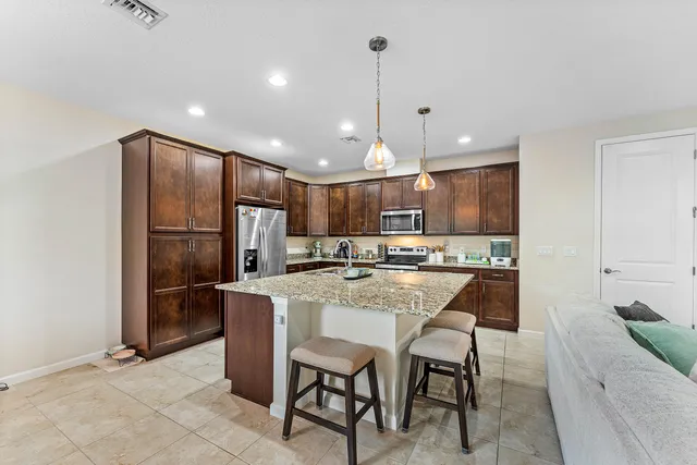 a kitchen with kitchen island a dining table chairs stainless steel appliances and cabinets