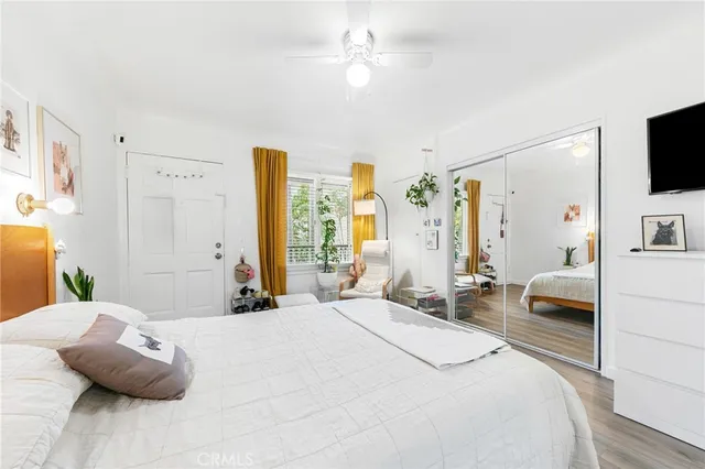 a bedroom with a bed wooden floor and a large window