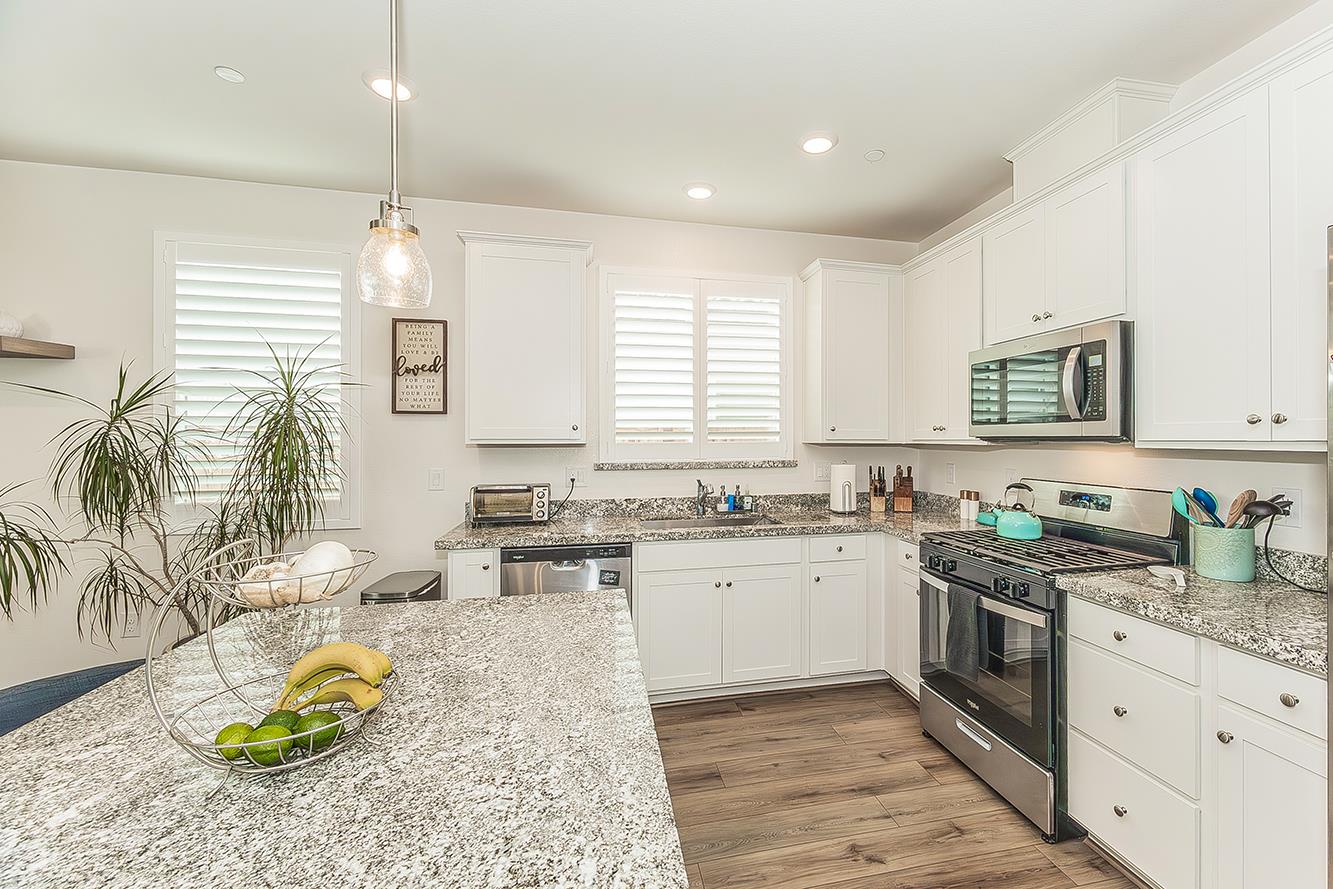 644 Rock Crest Avenue Madera, CA 93636 - Photo 14 of 38 a kitchen with a stove a sink a center island cabinets and furniture