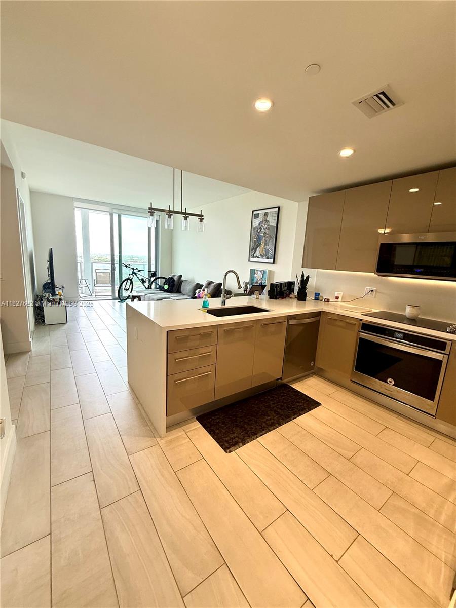 2000 Metropica Way, Unit 1605 Sunrise, FL 33323 - Photo 3 of 43 a kitchen with stainless steel appliances a sink a counter top space cabinets and a window