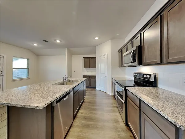 a kitchen with stainless steel appliances granite countertop a sink stove and refrigerator