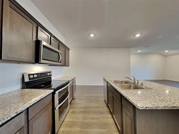 a kitchen with stainless steel appliances granite countertop a sink wooden cabinets and granite counter tops