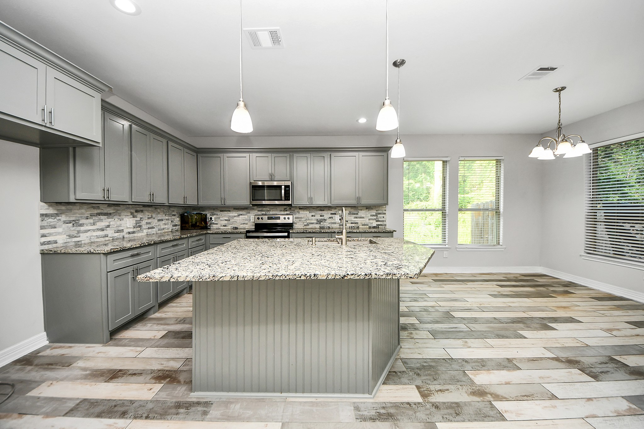 25450 Killarney Road Hempstead, TX 77445 - Photo 21 of 34 a kitchen with kitchen island granite countertop a stove a sink a refrigerator island and white cabinets with wooden floor