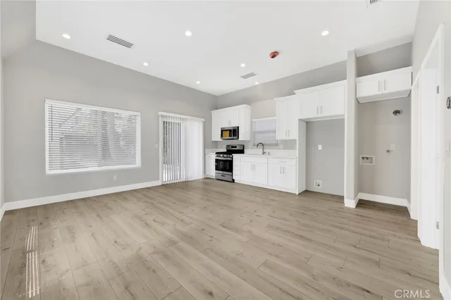 a view of a electric appliances in kitchen and empty room with wooden floor