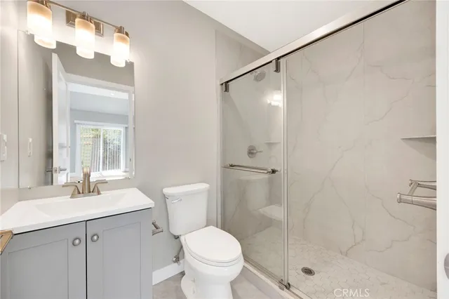 a bathroom with a shower sink vanity mirror and toilet