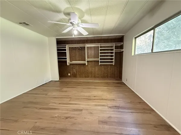a view of empty room with wooden floor and fan