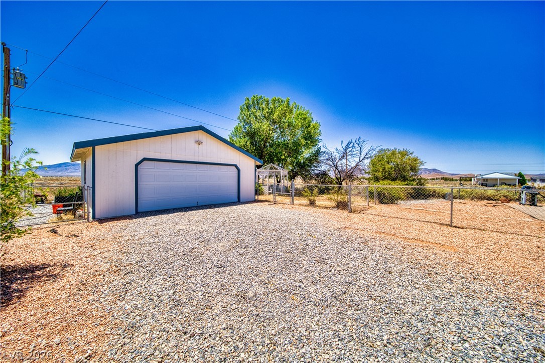 2931 Rio Rancho Drive, Unit 4 Pahrump, NV 89048 - Photo 3 of 21 A detached garage with ample gravel parking offers practical storage and vehicle accommodation.
