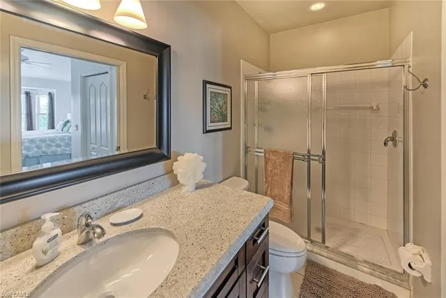 a bathroom with a granite countertop sink a mirror and shower