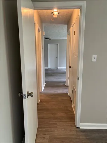a view of a hallway with wooden floor and a bathroom