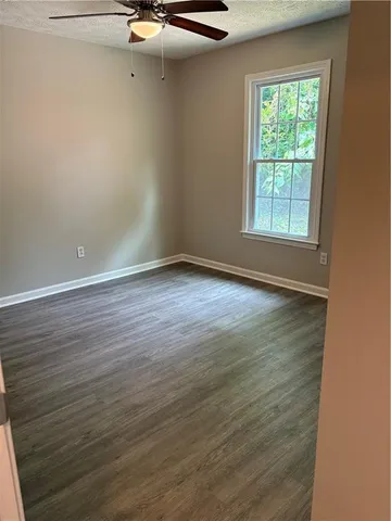 an empty room with wooden floor cabinet and windows