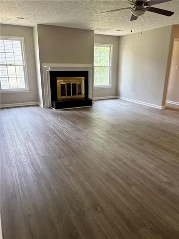 an empty room with wooden floor fireplace and windows