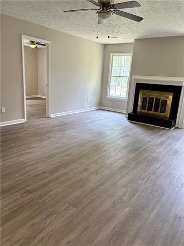 an empty room with wooden floor fireplace and windows