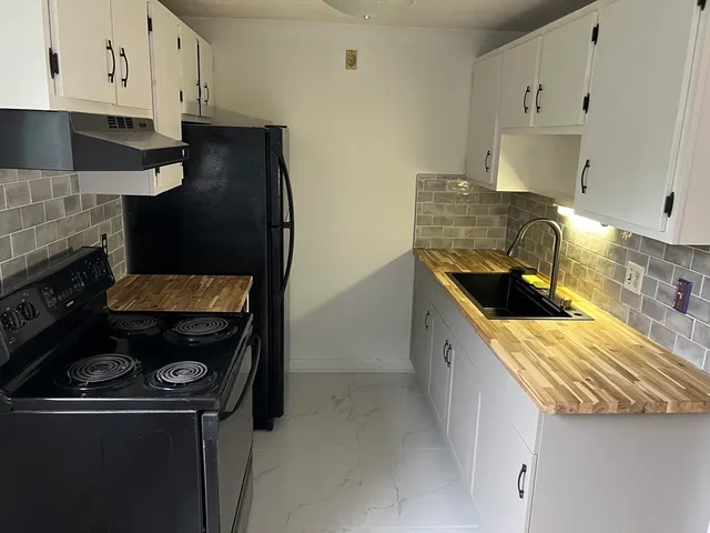 a kitchen with granite countertop a stove sink and cabinets